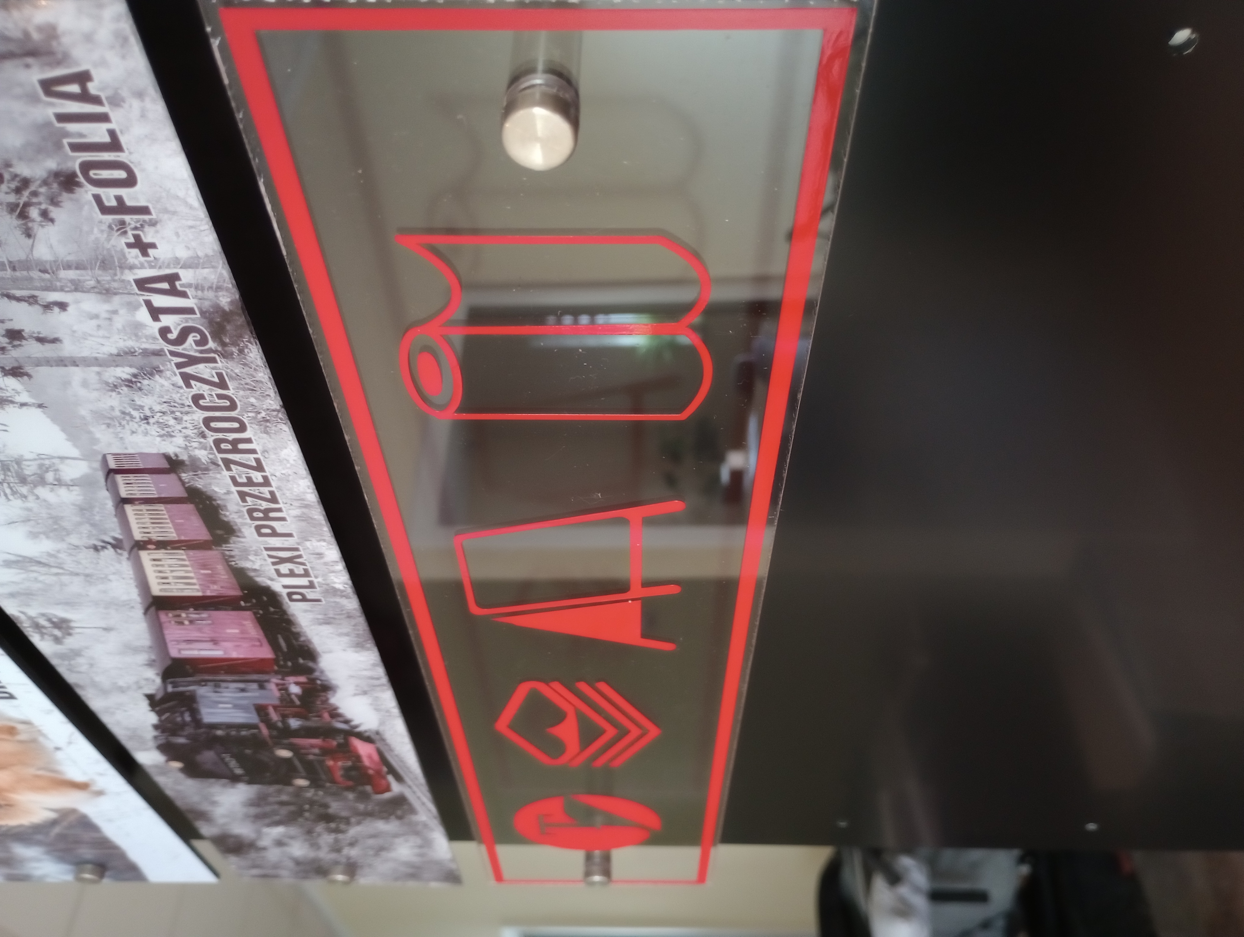 Czerwona grafika z folii ploterowej na przezroczystej płycie plexi